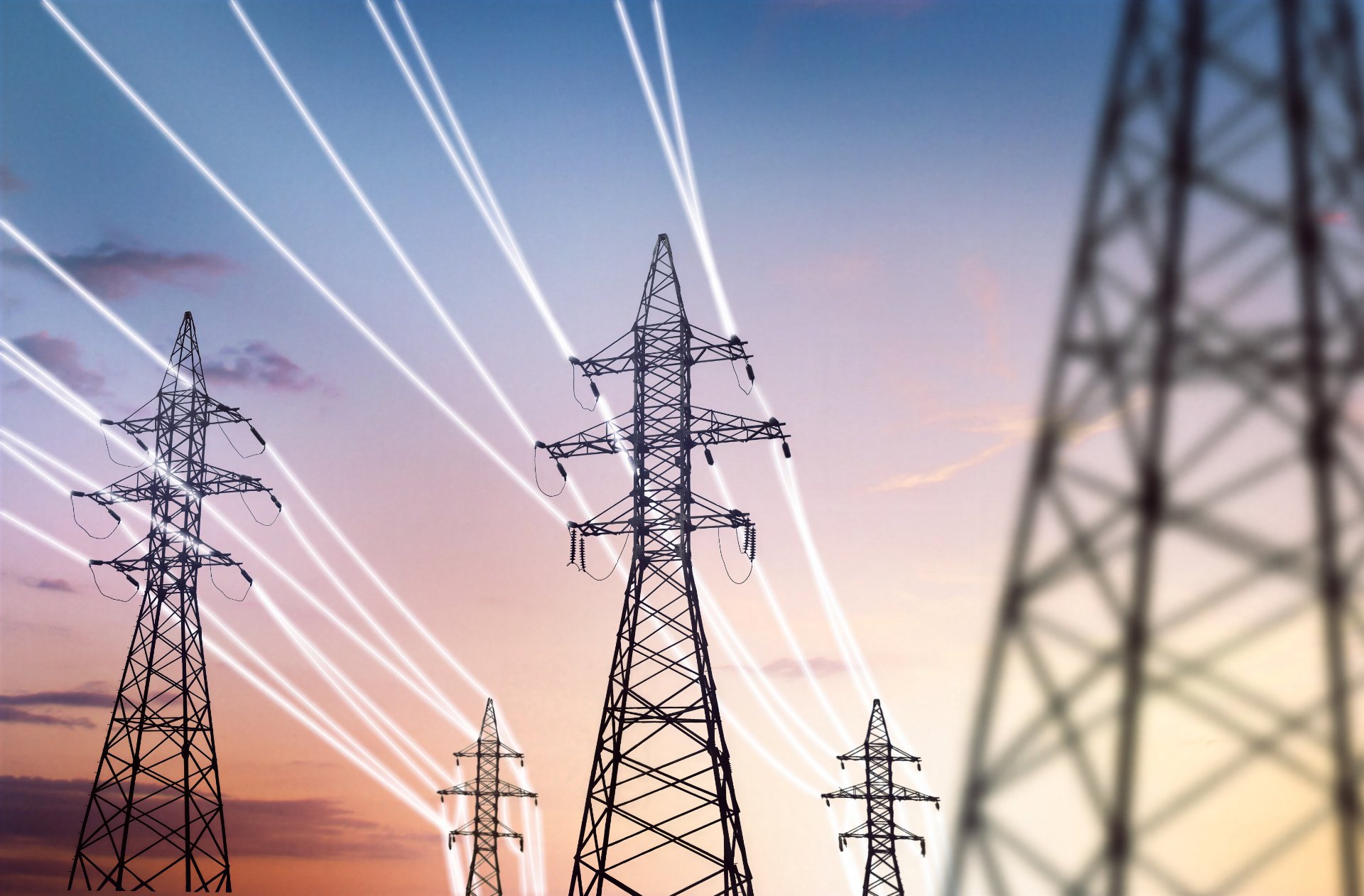 High-voltage transmission tower and power lines against a dusk sky.